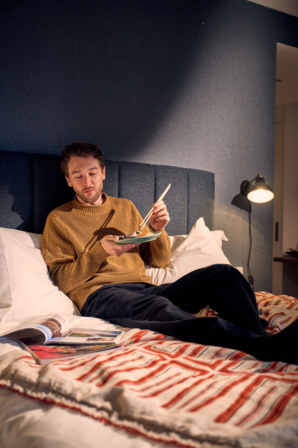 A guy eating a meal in bed 